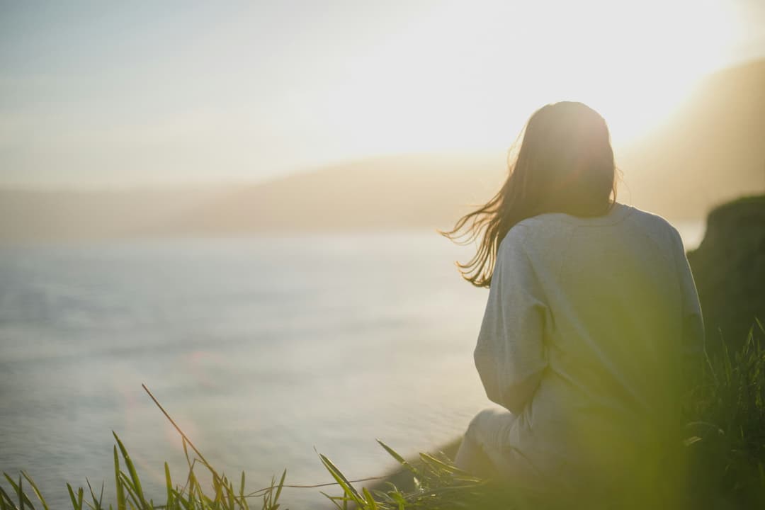 woman wearing gray long sleeved shirt facing the sea woman wearing gray long sleeved shirt facing the sea