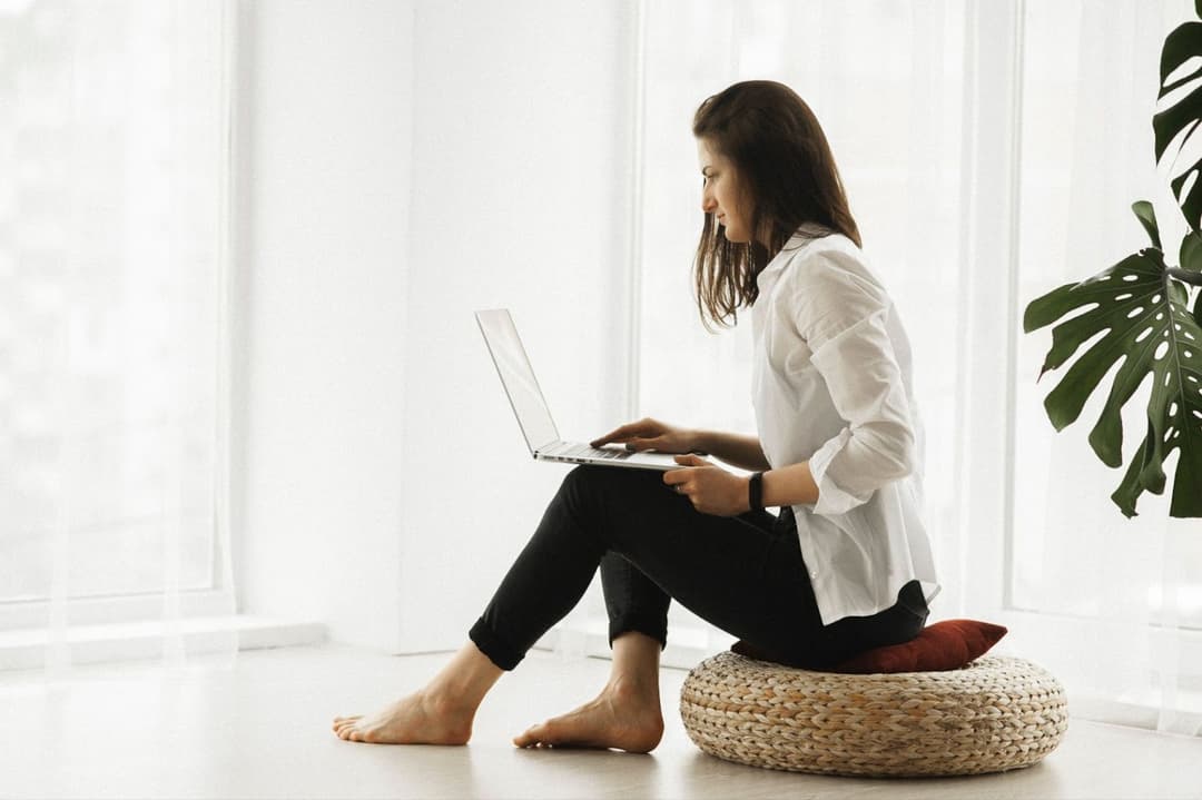 Woman in white long sleeve shirt and black pants sitting on brown woven chair Woman in white long sleeve shirt and black pants sitting on brown woven chair